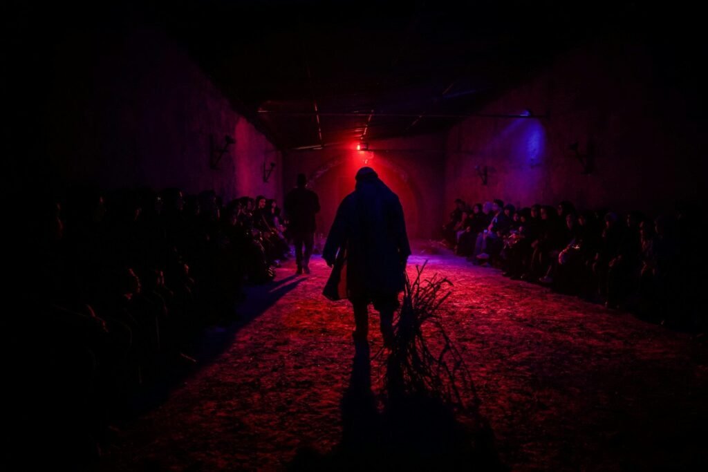 A person walks down a dark, red-lit hallway.